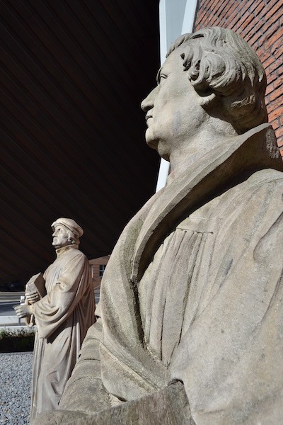 Fotos zweier Statuen der Reformatoren Zwingli und Luther